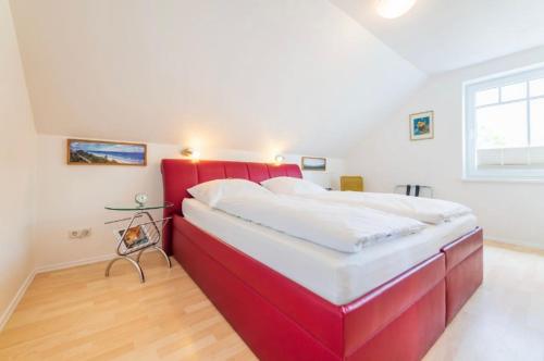 een groot rood bed in een witte slaapkamer bij Villa Judith App. 3 Silbermöwe in Binz