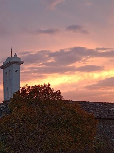 a clock tower on top of a roof with a sunset at Chambre d'hôtes couvent d'Alando in Alando