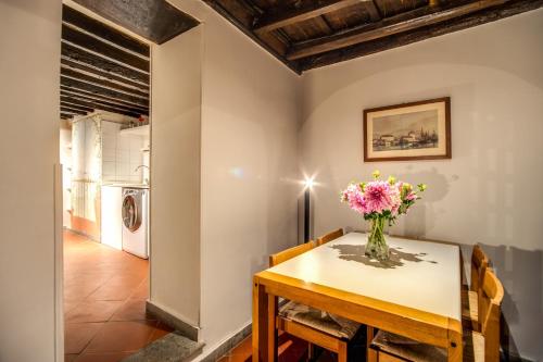 uma sala de jantar com uma mesa e um vaso de flores em Cartari Apartment em Roma