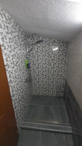 y baño con ducha y pared de azulejos. en Planinske kolibe Šipovo, en Šipovo