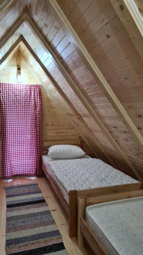 a small attic bedroom with a bed and a rug at Planinske kolibe Šipovo in Šipovo