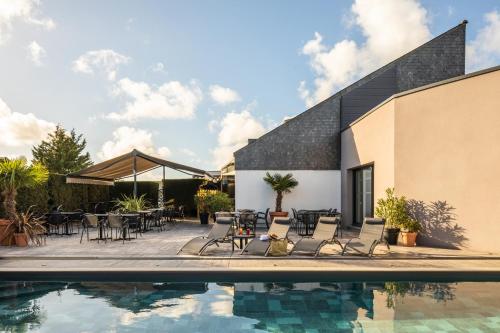 uma piscina com cadeiras e mesas ao lado de um edifício em ibis Saint-Nazaire - Trignac em Trignac