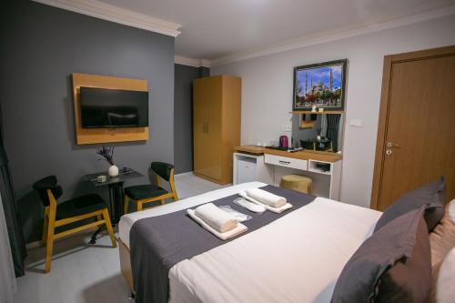 a bedroom with a bed and a desk and a tv at BLAU GRÜN İSTANBUL OTEL in Istanbul