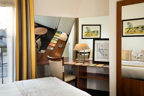 a hotel room with a desk and a bed at Grand Hotel des Balcons in Paris