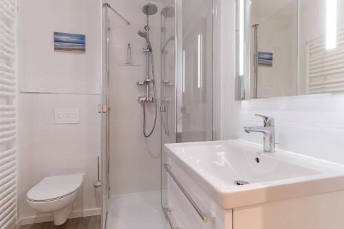 ein weißes Bad mit einem Waschbecken und einer Dusche in der Unterkunft Beach Lodge Beach Lodge Appartement 6 in Sankt Peter-Ording