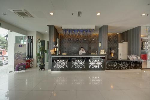 a woman standing behind a counter in a lobby at Arenaa Deluxe Hotel in Melaka