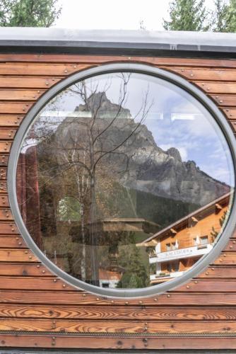 a round window with a reflection of a mountain at Typically Swiss Hotel Ermitage in Kandersteg