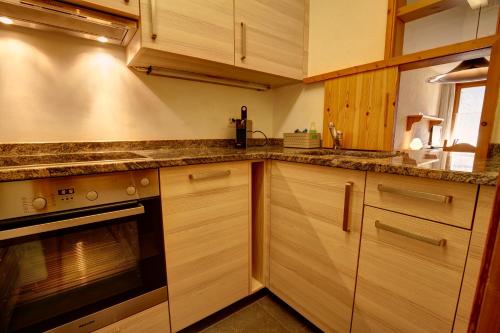 a kitchen with wooden cabinets and a stove at Chesa Munteratsch 1-Zimmerwohnung 203 Typ B in Silvaplana
