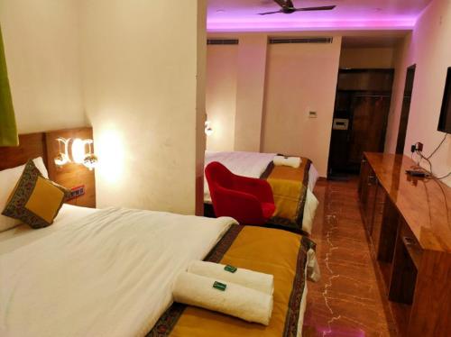 a hotel room with two beds and a red chair at Namaste Benares Varanasi in Varanasi