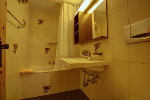 a bathroom with a sink and a bath tub at Chesa Munteratsch 2-Zimmerwohnung 105 Typ E in Silvaplana