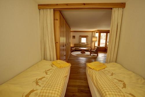 a bedroom with two beds and a living room at Chesa Munteratsch 1 1 2-Zimmerwohnung 409 Typ C in Silvaplana