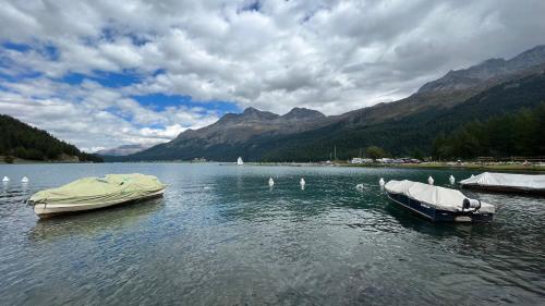 two boats on a lake with mountains in the background at Chesa Munteratsch 1 1 2-Zimmerwohnung 409 Typ C in Silvaplana