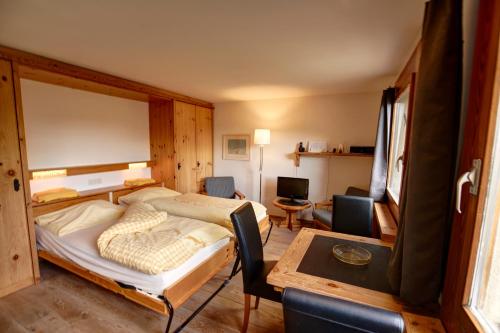 a bedroom with a bed and a table and chairs at Chesa Munteratsch 1-Zimmerwohnung 411 Typ A in Silvaplana