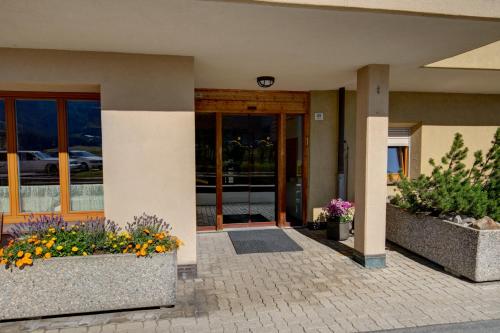a building with two large flower pots in front of it at Chesa Munteratsch 1 1 2-Zimmerwohnung 209 Typ D in Silvaplana
