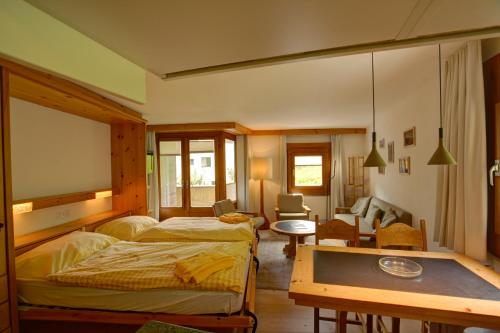 ein Schlafzimmer mit zwei Betten und einem Tisch darin in der Unterkunft Chesa Munteratsch 2-Zimmerwohnung 410 Typ E in Silvaplana