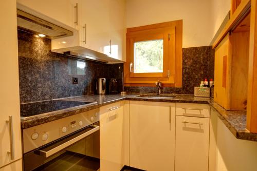 a kitchen with white cabinets and a sink at Chesa Munteratsch 2-Zimmerwohnung 301 Typ E in Silvaplana