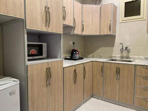 a kitchen with wooden cabinets and a microwave at Staytion Express Orjwan Lebanon in Jeddah