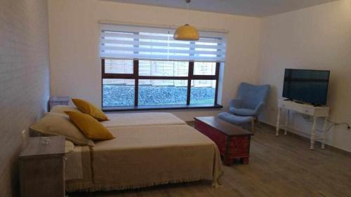 a bedroom with a bed and a television and a chair at Chijere San Sebastián in San Sebastián de la Gomera
