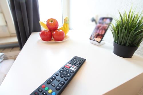 a remote control sitting on a table next to a bowl of fruit at Downtown Apartments Ulm - im Herzen von Ulm & komfortable Boxspringbetten in Ulm