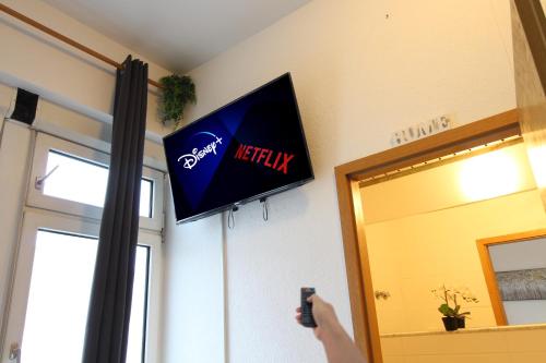a person taking a picture of a television on a wall at Downtown Apartments Ulm - im Herzen von Ulm & komfortable Boxspringbetten in Ulm
