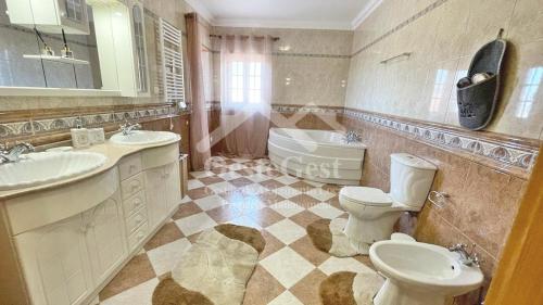 y baño con 2 lavabos, aseo y bañera. en Villa Arrifes, en Reguengo Grande