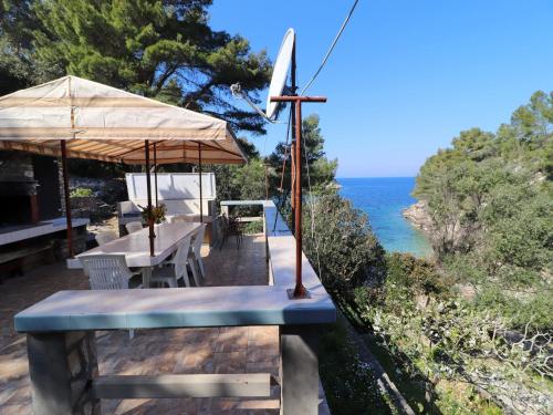 une terrasse avec une table et un parasol et l'océan dans l'établissement Holiday House Danica, à Vela Luka