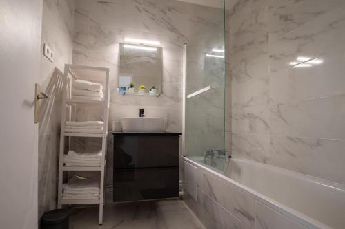 une salle de bain avec un lavabo, une baignoire et un miroir dans l'établissement Grand 3 pièces Créteil -20minutes de Paris !, à Créteil