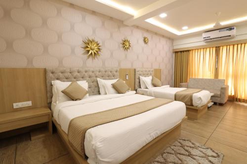 a hotel room with two beds and a couch at Hotel PTC in Indore