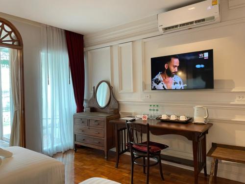 a hotel room with a table and a tv on the wall at Wiang Ville Boutique Hotel in Chiang Mai