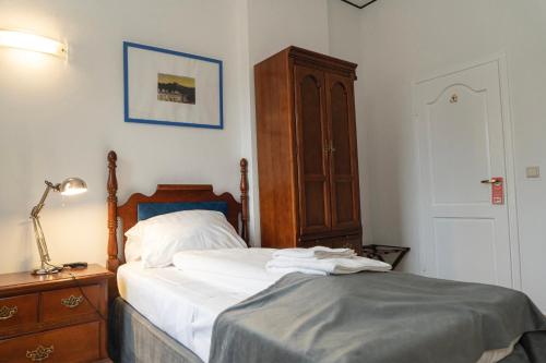 a bedroom with a bed and a lamp and a dresser at Hotel Petit Wannsee in Berlin