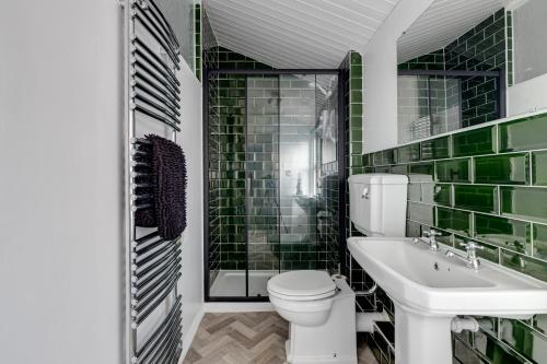 La salle de bains est pourvue de carrelage vert, de toilettes et d'un lavabo. dans l'établissement Sandy House, à Scarborough