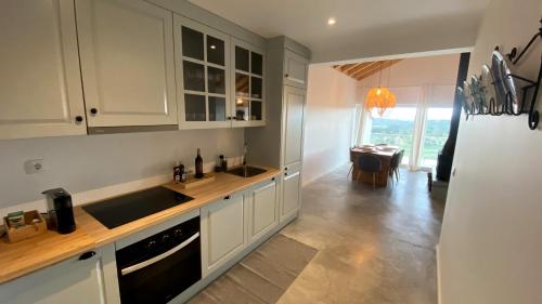 a kitchen with white cabinets and a sink and a table at Casas Fonte da Tapada - Casa da Fonte in Trancoso