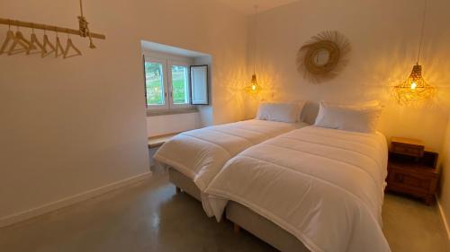 a bedroom with a large white bed with a mirror at Casas Fonte da Tapada in Trancoso