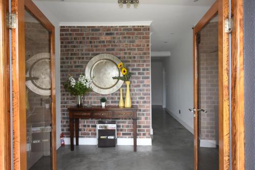 um quarto com uma parede de tijolos e uma mesa com flores em OnQ Accommodation em Bellville