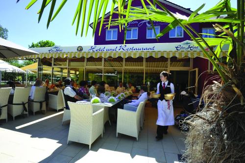 a woman is standing in front of a restaurant at Eden Hotel in Bad Krozingen