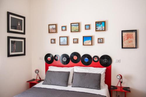 a bedroom with a red headboard with pictures on the wall at Grammy Suite in Rome
