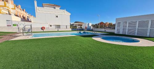 un patio trasero con piscina y césped verde en Chalet Francisco, en San Juan de los Terreros