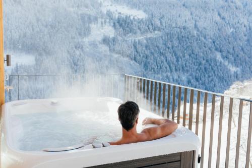 a man sitting in a hot tub on a balcony at Boutique Apartment Sonnenhang - incl InfinityPOOL in Fliess