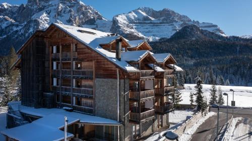 a lodge in the snow with mountains in the background at Maribel Hotel in Madonna di Campiglio