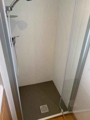 d'une cabine de douche avec une porte en verre et un orifice de vidange dans l'établissement RESPIRE, à Quiberon