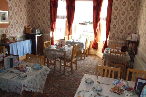 ein Esszimmer mit Tischen, Stühlen und Fenstern in der Unterkunft Copperfields Guest House in Great Yarmouth