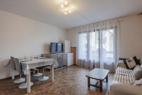 - un salon avec une table, une télévision et un canapé dans l'établissement Les Narcisses - aux pieds des pistes, à Saint-Léger-les-Mélèzes