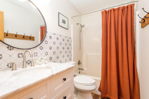 a bathroom with a sink and a toilet and a mirror at House on Honeysuckle in Pisgah Forest