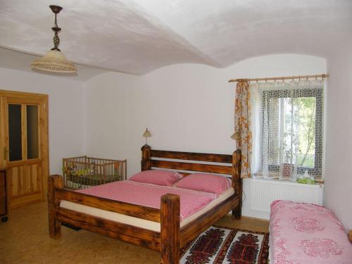 a bedroom with a wooden bed with pink sheets at Bezbariérové ubytování na statku in Kájov