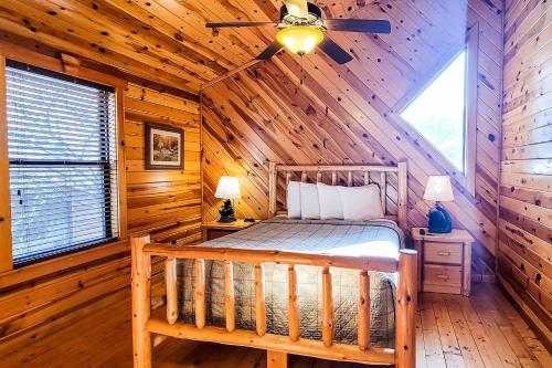 1 dormitorio en una cabaña de madera con 1 cama y ventilador de techo en Serenity Now, en Gatlinburg