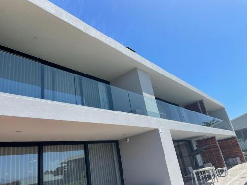 a building with glass windows and a balcony at Hilltop Bayview Luxury Apartments in Plettenberg Bay