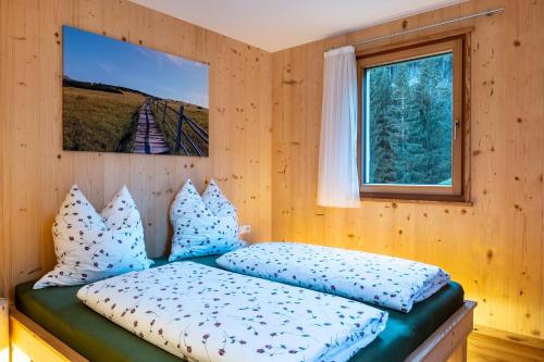 Un dormitorio con una cama con almohadas azules y una ventana en Mittnackerhof Apartment Ringelblume, en Sarentino