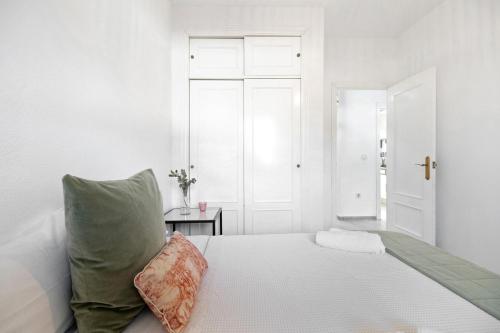 ein weißes Schlafzimmer mit einem Bett und einem Kissen in der Unterkunft Apartamento Calas Sancti Petri in Novo Sancti Petri