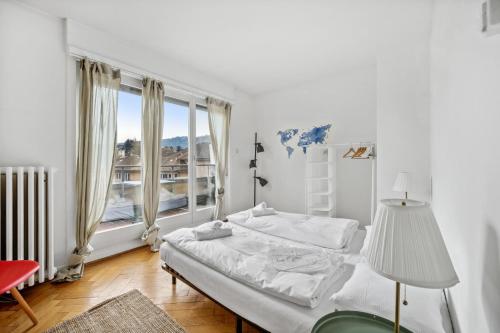 biała sypialnia z łóżkiem i dużym oknem w obiekcie Central Apartment for City Explorers 222 w Zurychu