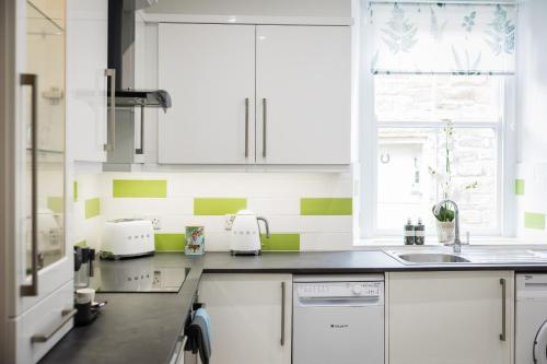 uma cozinha com armários brancos e riscas verdes e brancas em The Old Packhorse em Staindrop